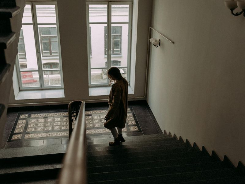 Person in a calm, focused state during a floor exercise in a minimalist dark room.